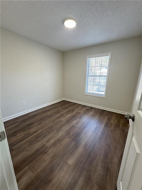 spare room featuring dark wood finished floors, baseboards, and a textured ceiling