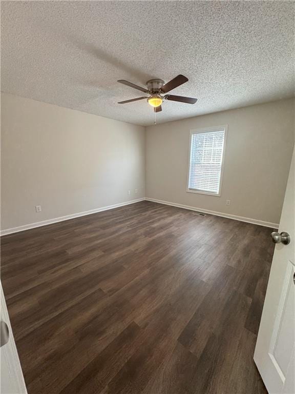 empty room with baseboards, a textured ceiling, dark wood-style floors, and a ceiling fan