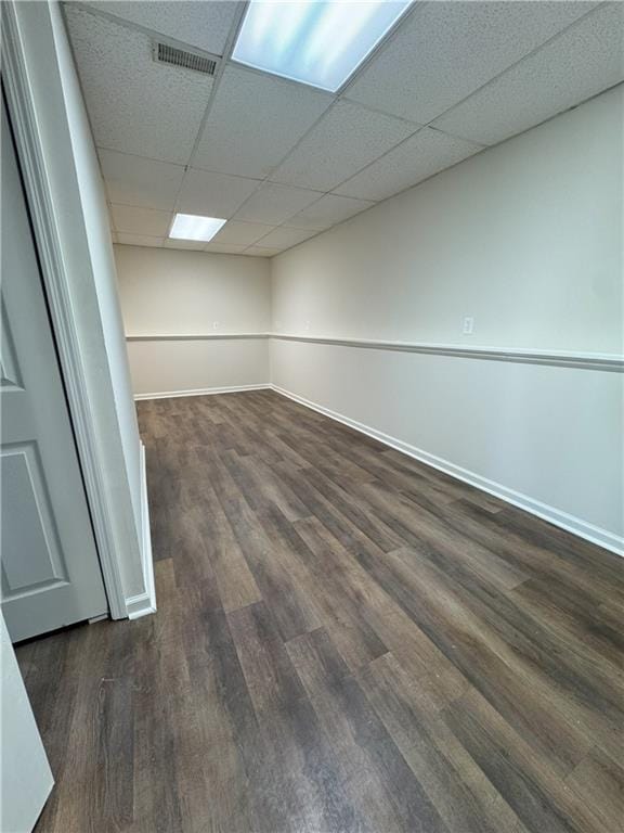 interior space featuring baseboards, visible vents, dark wood-style flooring, and a paneled ceiling