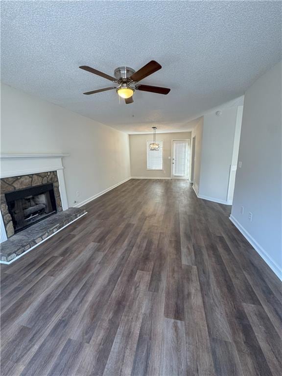 unfurnished living room featuring ceiling fan, a textured ceiling, dark wood-style flooring, and a fireplace