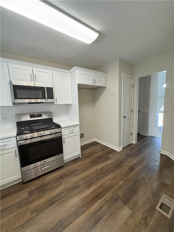 kitchen featuring visible vents, light countertops, white cabinets, dark wood-type flooring, and appliances with stainless steel finishes