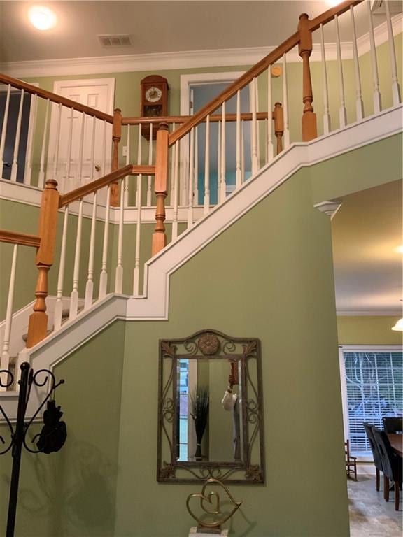 staircase featuring a high ceiling and crown molding