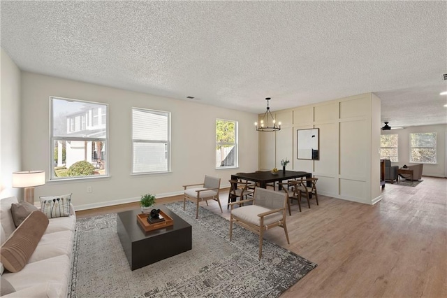 living room with a healthy amount of sunlight, hardwood / wood-style floors, a notable chandelier, and a textured ceiling