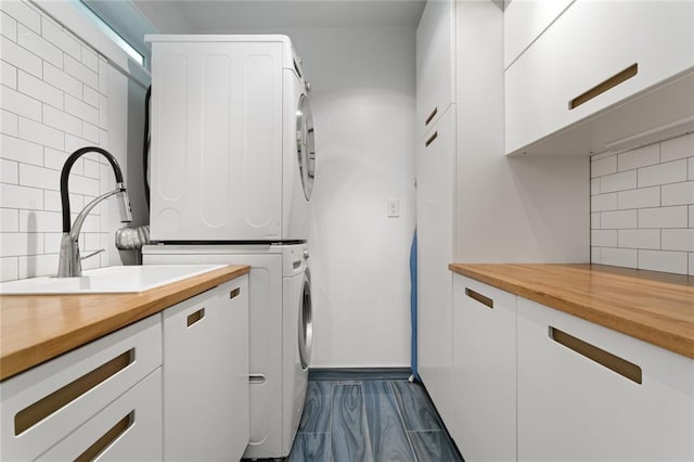 washroom with dark wood-style floors, stacked washer / drying machine, and cabinet space