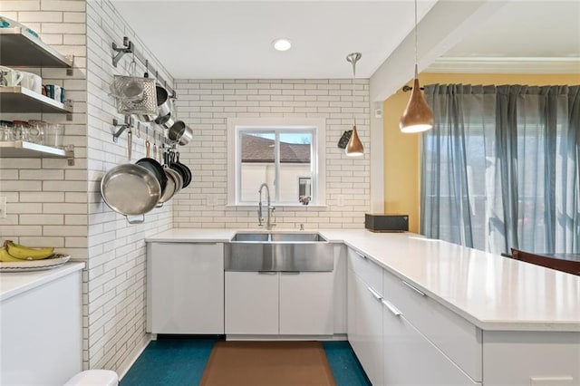 kitchen with white cabinets, a peninsula, light countertops, and a sink