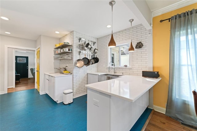 kitchen featuring a sink, a peninsula, and brick wall