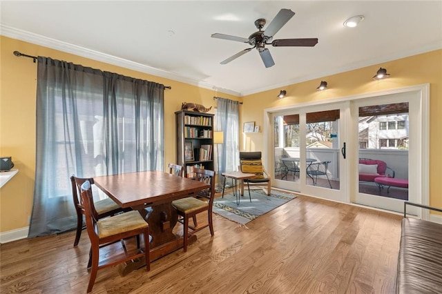 dining room with baseboards, wood finished floors, a ceiling fan, and crown molding