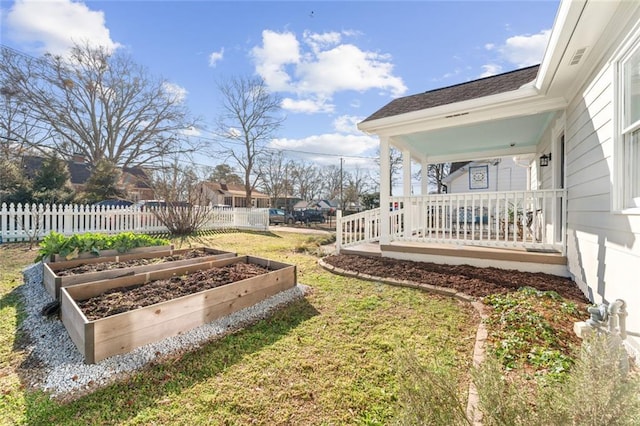 view of yard with a porch, a vegetable garden, and fence