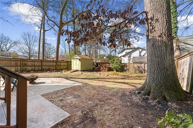 view of yard with a fenced backyard, a storage unit, and an outbuilding