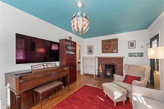 living area featuring a chandelier, ornamental molding, wood finished floors, and a wood stove