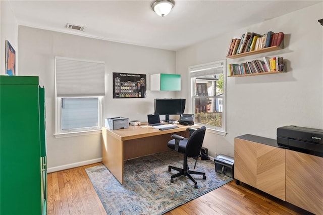 home office featuring wood-type flooring, visible vents, and baseboards