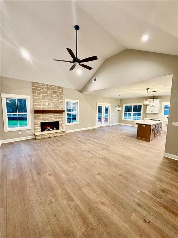 unfurnished living room featuring a ceiling fan, visible vents, light wood finished floors, and baseboards