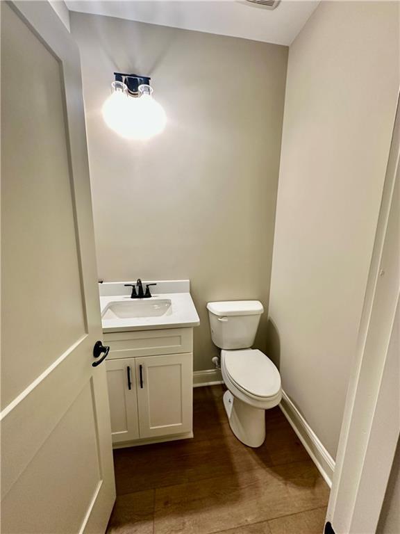 bathroom featuring vanity, toilet, wood finished floors, and baseboards