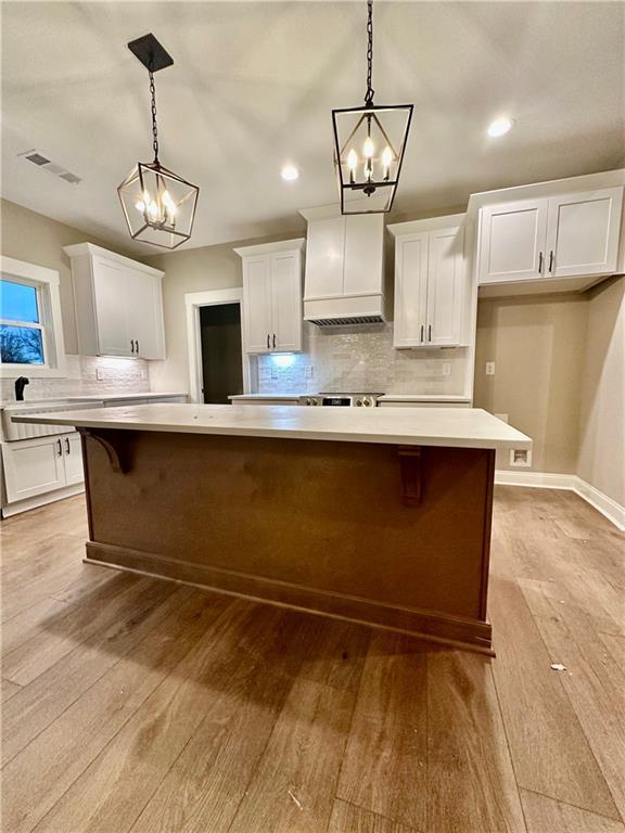 kitchen featuring visible vents, white cabinets, light countertops, and premium range hood