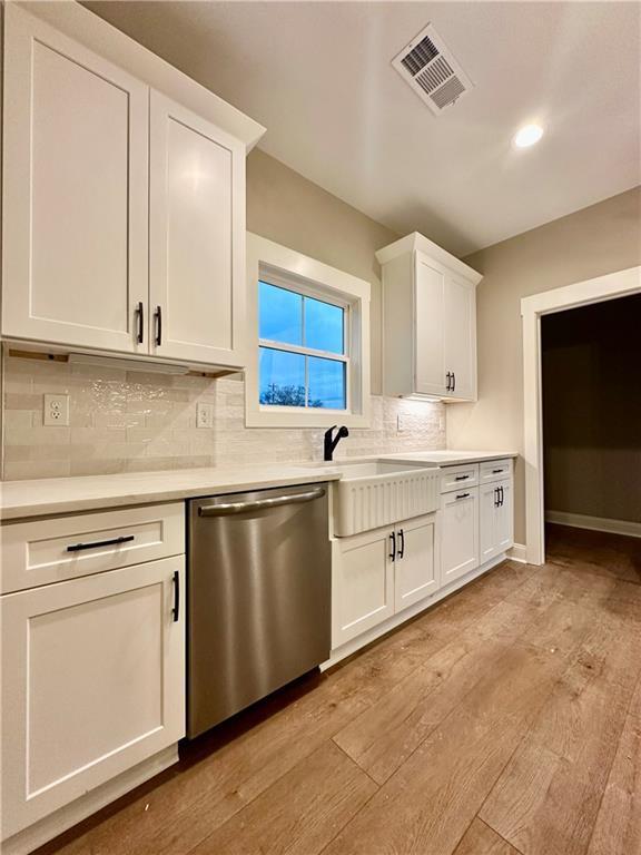 kitchen with visible vents, light wood finished floors, light countertops, white cabinets, and dishwasher