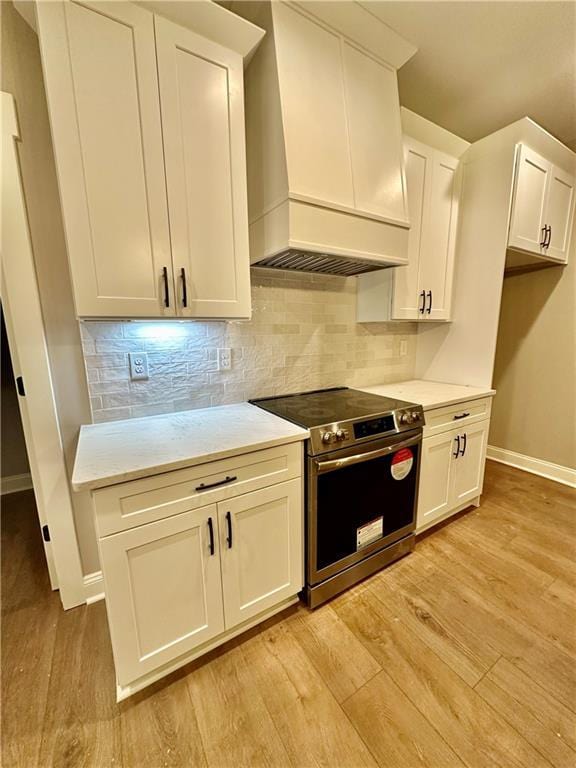 kitchen featuring light countertops, custom range hood, light wood-style flooring, and stainless steel range with electric cooktop