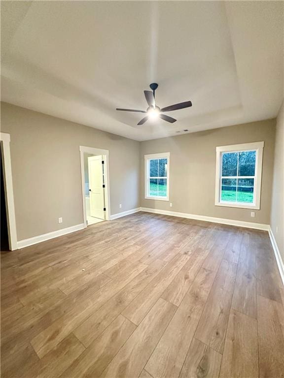 empty room featuring ceiling fan, baseboards, and wood finished floors