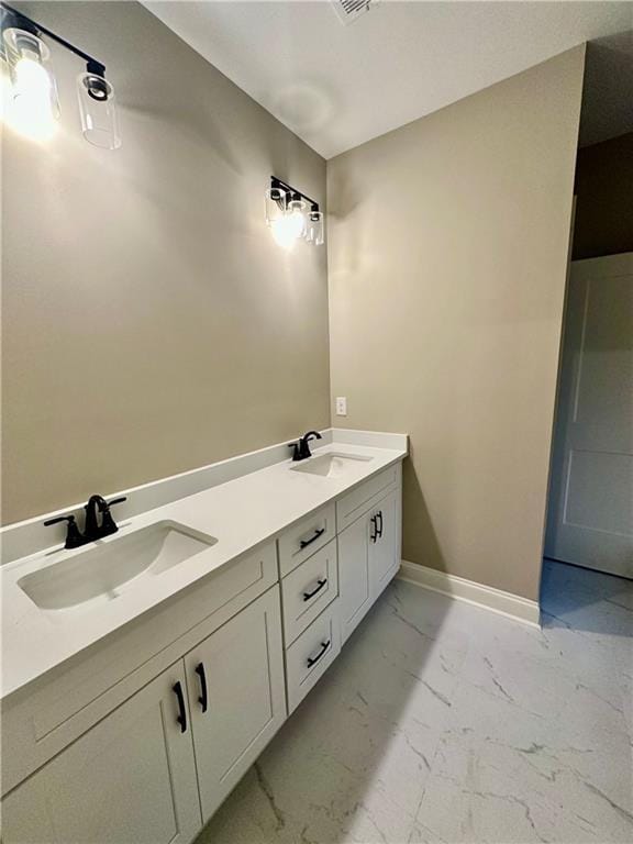 bathroom featuring double vanity, baseboards, marble finish floor, and a sink