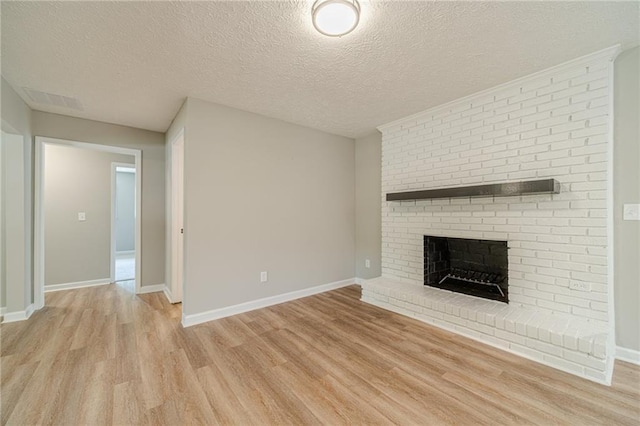 unfurnished living room with light wood-style floors, a fireplace, a textured ceiling, and baseboards
