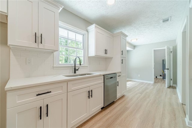 kitchen featuring dishwasher, a sink, backsplash, a textured ceiling, and white cabinetry