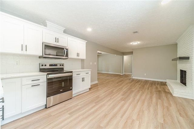 kitchen featuring stainless steel appliances, open floor plan, backsplash, light wood finished floors, and light countertops