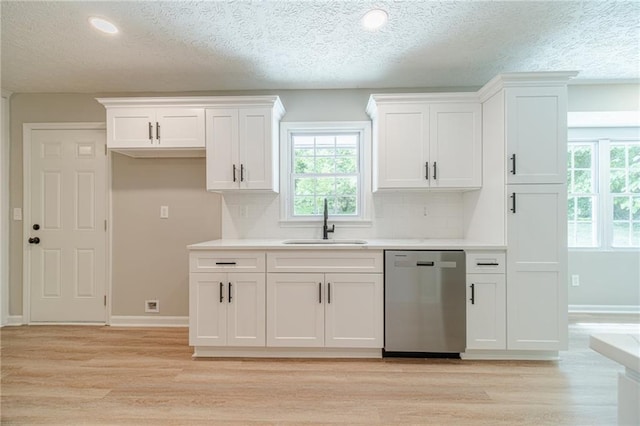 kitchen featuring dishwasher, a sink, light wood-style flooring, decorative backsplash, and a textured ceiling