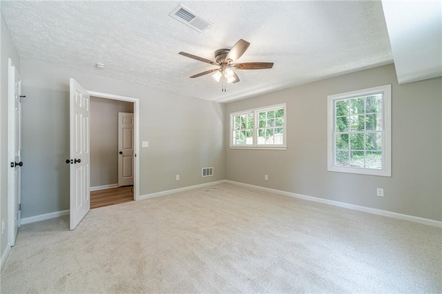 unfurnished bedroom with a textured ceiling, light colored carpet, baseboards, and a ceiling fan