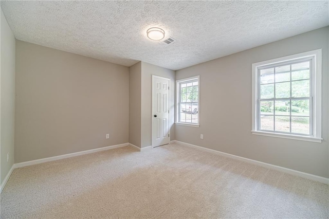 unfurnished room with light colored carpet, baseboards, and a textured ceiling