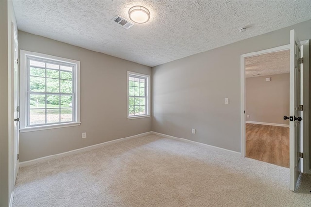 unfurnished room featuring a textured ceiling, carpet floors, baseboards, and a smoke detector
