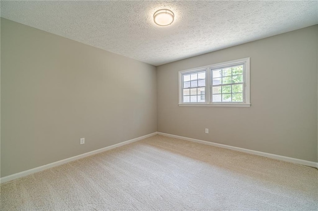 carpeted empty room featuring baseboards and a textured ceiling