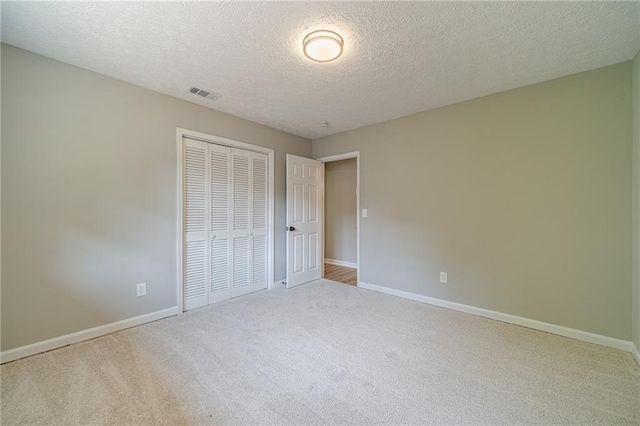 unfurnished bedroom with carpet, a closet, baseboards, and a textured ceiling