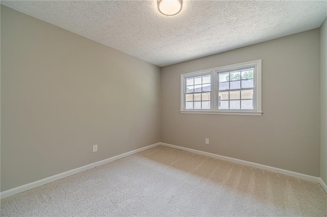 spare room featuring carpet floors, baseboards, and a textured ceiling