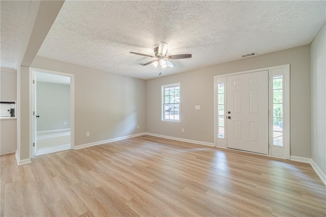 foyer with light wood-type flooring, ceiling fan, baseboards, and a textured ceiling