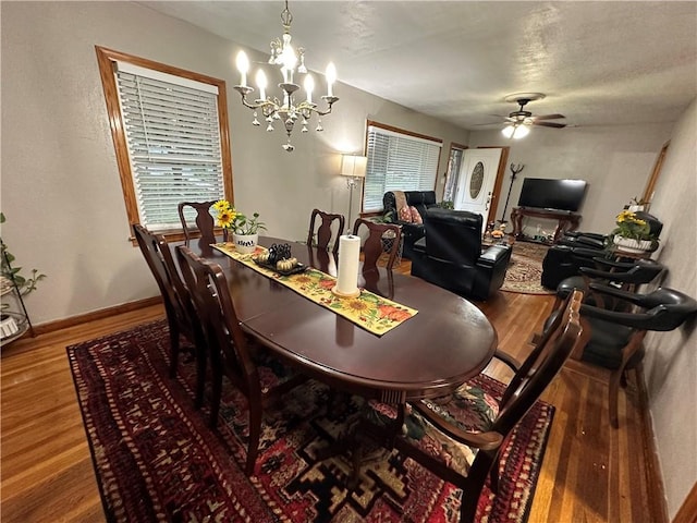 dining space featuring hardwood / wood-style flooring and ceiling fan with notable chandelier