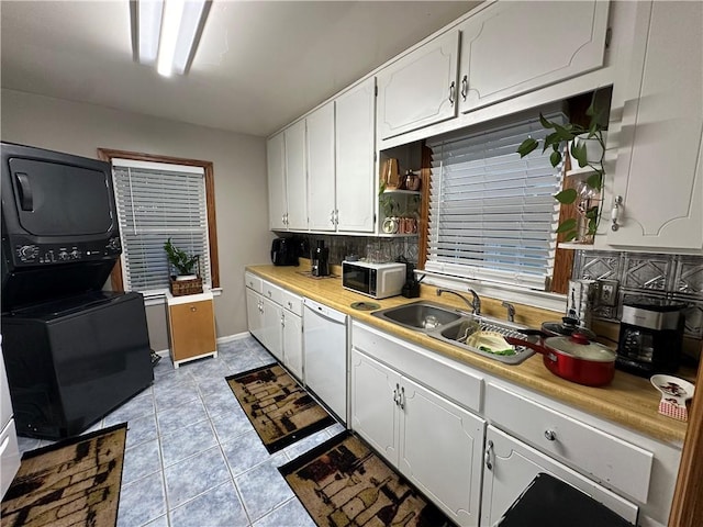 kitchen with sink, tasteful backsplash, stacked washer / dryer, white appliances, and white cabinets