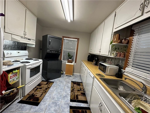 kitchen featuring white cabinetry, sink, backsplash, stacked washer / dryer, and white appliances