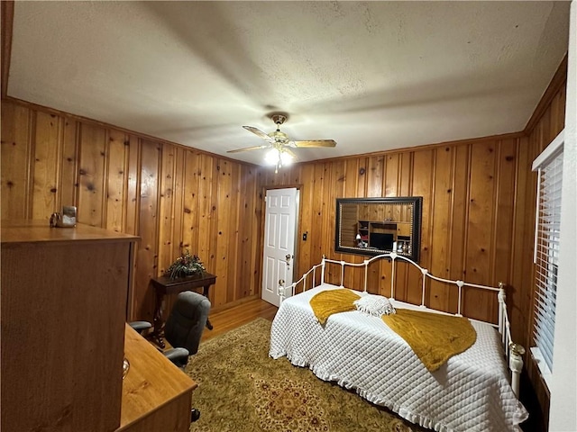 bedroom with hardwood / wood-style flooring, ceiling fan, crown molding, and wood walls