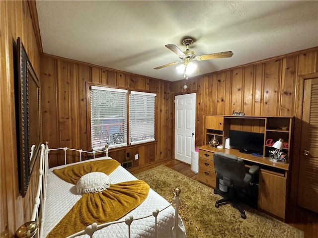 office with wood-type flooring, ornamental molding, ceiling fan, and wooden walls