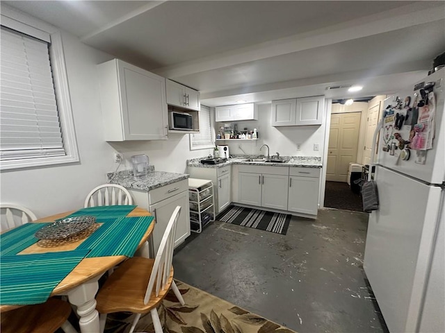 kitchen with white refrigerator, light stone counters, white cabinetry, and sink