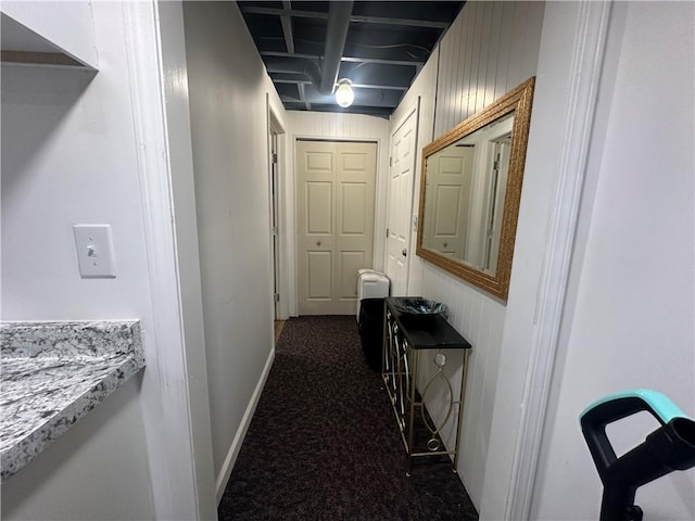 hallway with wood walls and dark colored carpet