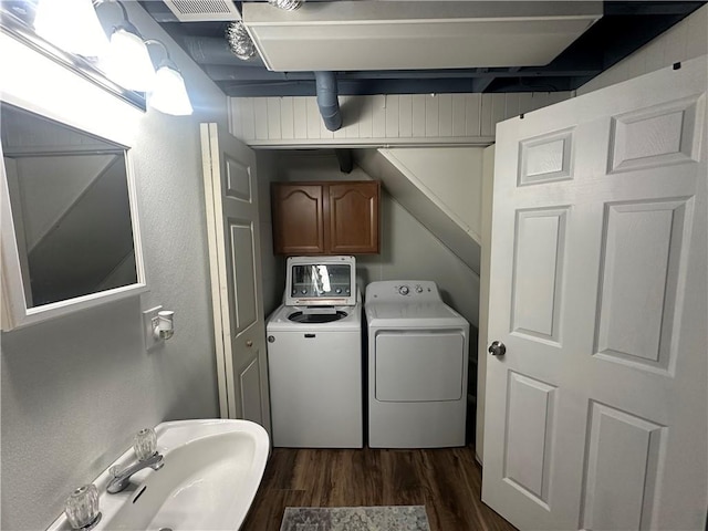 clothes washing area with washer and clothes dryer, dark hardwood / wood-style floors, and sink