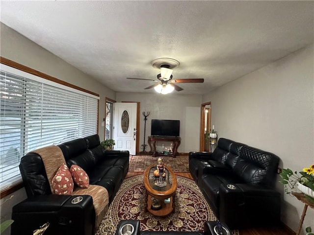 living room featuring ceiling fan and a textured ceiling