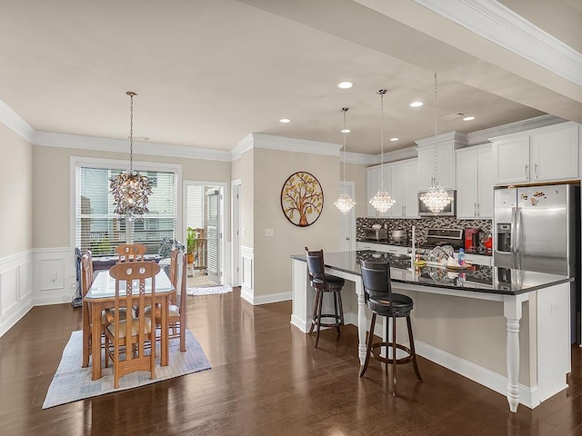 kitchen featuring a kitchen island, a breakfast bar, white cabinetry, hanging light fixtures, and dark wood-type flooring