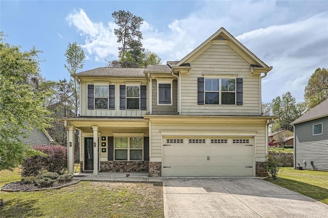 craftsman inspired home with a front yard, an attached garage, stone siding, and concrete driveway