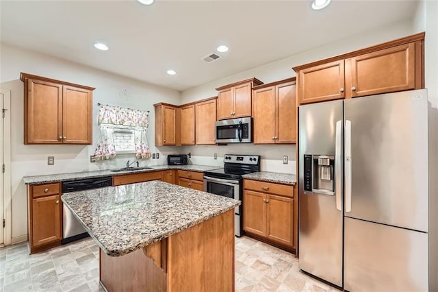 kitchen with a sink, visible vents, appliances with stainless steel finishes, and brown cabinets