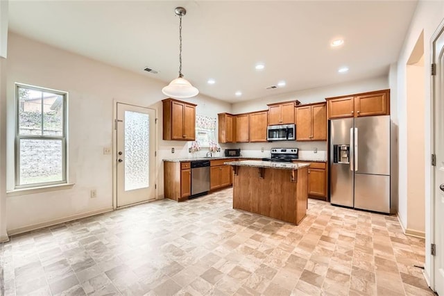 kitchen with recessed lighting, a kitchen island, brown cabinetry, stainless steel appliances, and hanging light fixtures