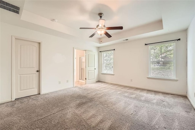 unfurnished bedroom with a tray ceiling, multiple windows, and visible vents