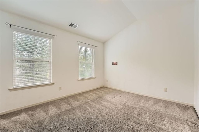 carpeted empty room featuring baseboards, lofted ceiling, and visible vents