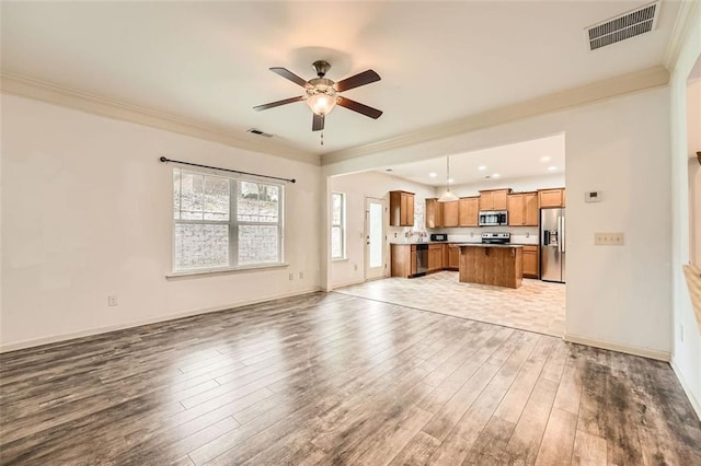 unfurnished living room featuring visible vents, ornamental molding, light wood-style flooring, and ceiling fan