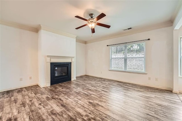 unfurnished living room featuring ceiling fan, ornamental molding, visible vents, a glass covered fireplace, and wood finished floors